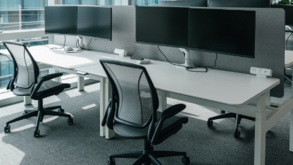 a modern, open-plan office space filled with natural light from large windows that offer a view of the cityscape.