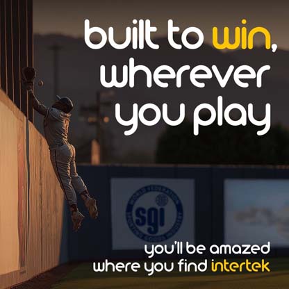 Uniformed player jumping near back wall of baseball field to catch a ball